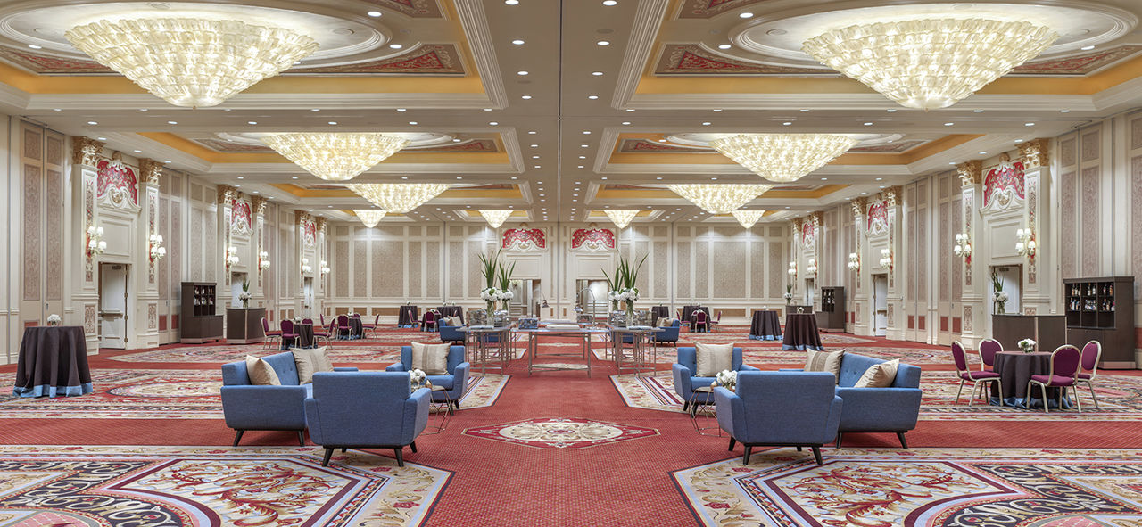 Interior of a ballroom with tables, chairs, chandeliers, and a bar at the Venetian Resort.